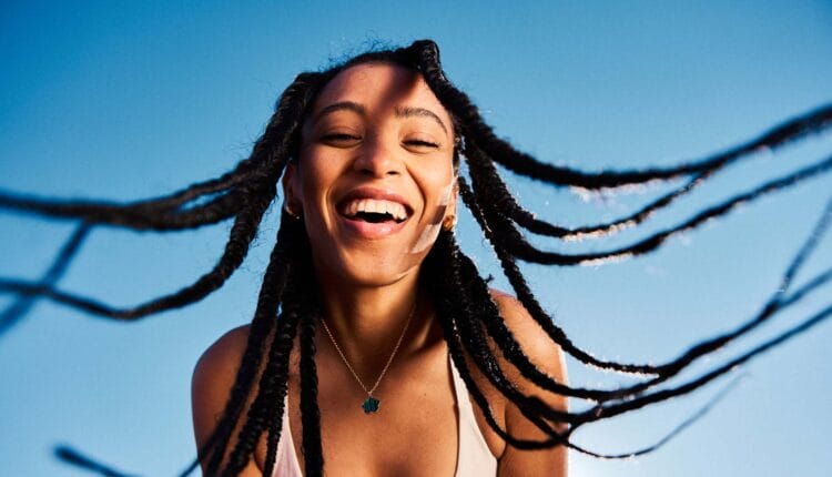 Portrait of attractive young woman tossing her long braided hair and being happy